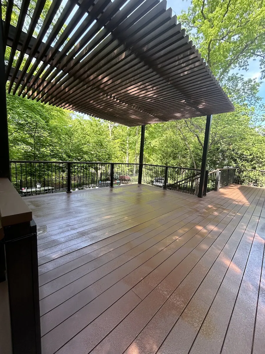 Stained wood deck under a pergola, with trees all around.